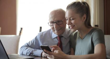 Older gentleman being shown how to use a smartphone by a younger lady.jpeg