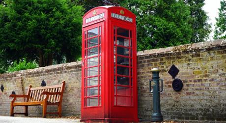 Red phone box next to a stone wall