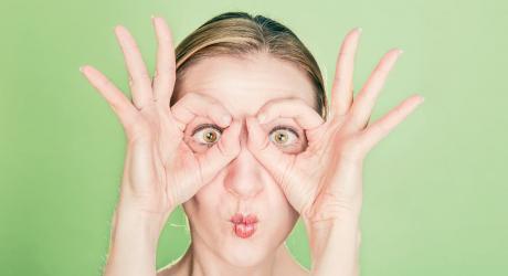 Woman holding her fingers to her eyes to mimic glasses