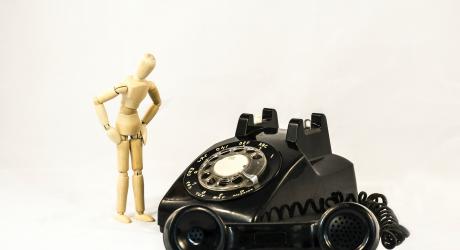 A wooden model next to an old telephone