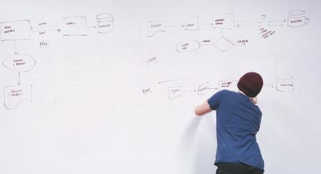 A man drawing a flow chart on a huge whiteboard