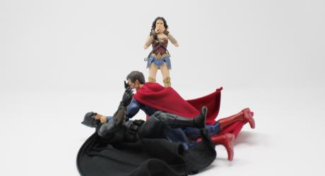 Superman fighting Batman whilst Wonder Woman watches.