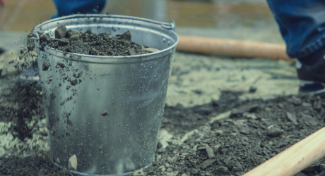 Bucket of dirt with a spade next to it