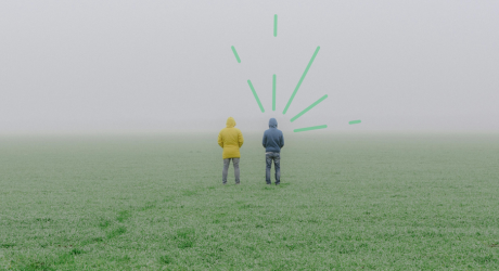 Two men in a field, and a cloudy view ahead of them