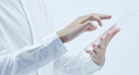 A person in a white lab coat holding a tablet